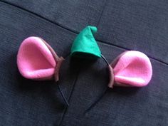 a pair of ears made out of felt are sitting on a bed with a green and pink hat