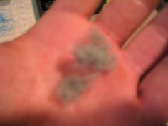 a close up of a person's left hand with small gray substance on it