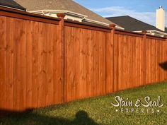 a wooden fence in front of a house with the name stain & seal expert written on it