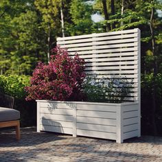 a white planter sitting on top of a brick floor next to a wooden bench