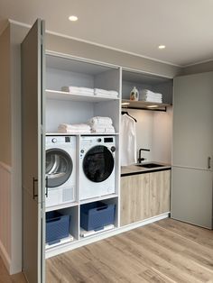 a washer and dryer in a room with wood flooring, open shelving