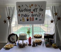 a white table topped with lots of cakes and desserts next to a sign that says, anything off the tolley dee's?