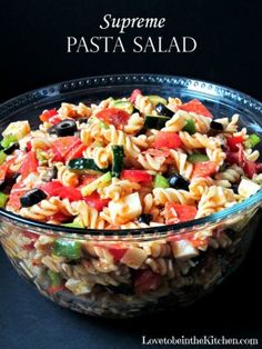 pasta salad in a glass bowl on a black background with the words supreme pasta salad above it