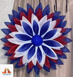 a red, white and blue flower is hanging on the wall