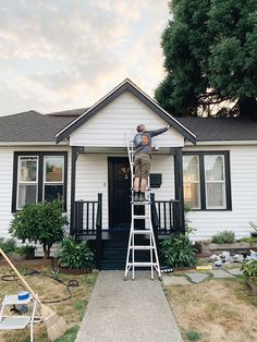 a man standing on a ladder in front of a house