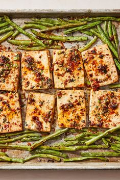 several square pieces of fish and asparagus on a baking sheet with seasoning