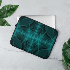 a laptop computer case sitting on top of a table next to a green leafy plant