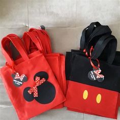 three bags with mickey mouse designs on them are sitting next to each other, one is red and the other is black