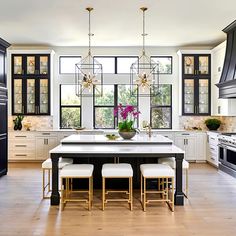 a large kitchen with white cabinets and black counter tops, along with an island in the middle