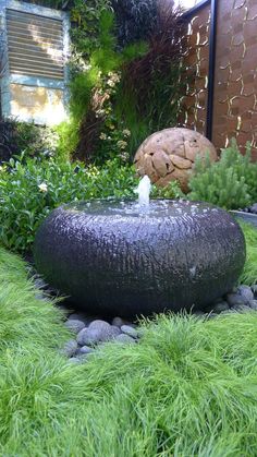 an outdoor fountain surrounded by grass and rocks