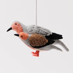 two birds are hanging from a string ornament on a white background and one bird has an orange beak