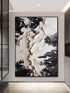 an abstract painting hangs in the corner of a room with black and white decor on the walls