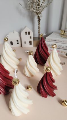 five red and white christmas trees on a table with gold bells in front of them