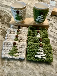 crocheted christmas coasters and cups on a table with coffee mugs in them