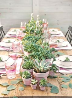 the table is set with succulents and wine glasses