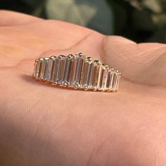 a woman's hand holding a ring with five baguettes