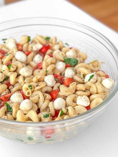 a glass bowl filled with pasta salad on top of a table