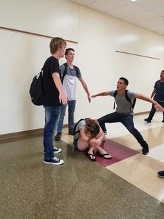 a group of young men standing around a woman laying on the floor in front of them