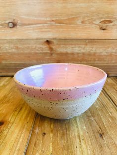 a pink and white bowl sitting on top of a wooden table