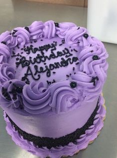 a purple frosted birthday cake sitting on top of a table