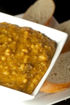 a white plate topped with bread and a bowl of soup