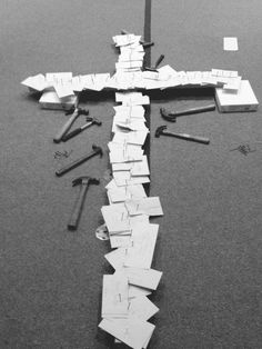 a cross that is laying on the ground with many pieces of paper taped to it