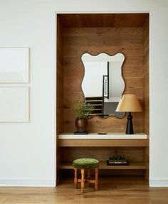 a room with a mirror, stool and lamp on the table in front of it