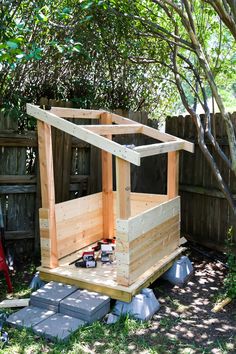 a wooden outhouse sitting in the middle of a yard with some tools on it