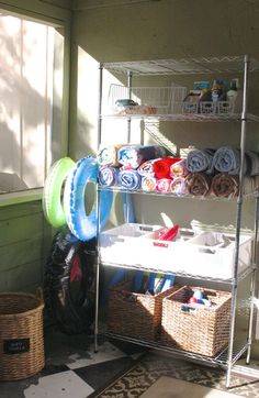 a shelf filled with lots of towels and other items next to a window in a room