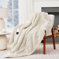 a white blanket sitting on top of a chair next to a fire place