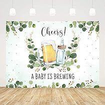 a baby is brewing sign on a wooden floor in front of a wall with greenery