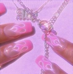 a woman's hand with pink and white nail designs on it, holding onto a chain