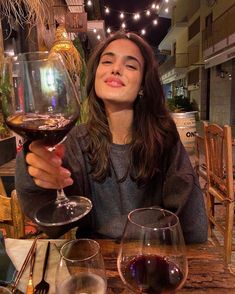 a woman sitting at a table with two glasses of wine