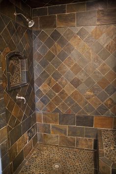 a tiled shower in a bathroom with brown and tan tiles on the wall next to it