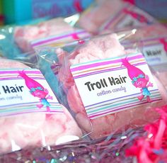 three bags of troll hair sitting on top of each other in front of some pink and blue streamers