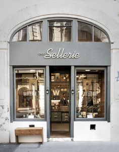 a store front with two windows and a bench in front of the entrance to it