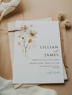 a wedding card with flowers on it next to a flower bouquet and some twine