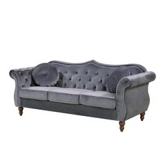 a grey velvet couch with buttons on the back and arms, sitting in front of a white background