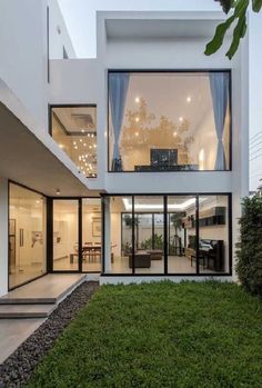 a modern house with large windows and grass in the front yard, as well as stairs leading up to the second floor