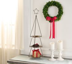 a christmas tree with a wreath on the wall next to candles and a candle holder