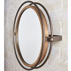 a round mirror mounted to the side of a wall next to a white brick wall