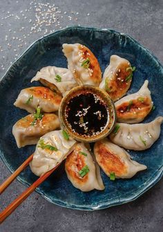 a blue plate topped with dumplings covered in sauce