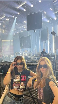 two beautiful young women standing next to each other in front of a stage with lights