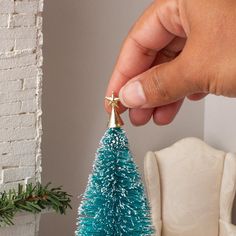 a hand holding a tiny blue christmas tree