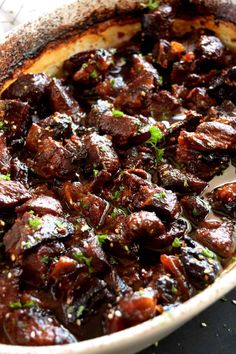 a dish filled with meat and garnish on top of a table