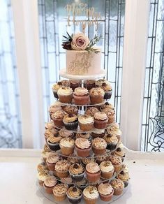 a three tiered cake with cupcakes on it