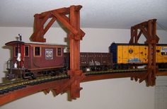 a toy train is on the tracks in a playroom with wooden beams and rails