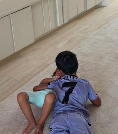 a young boy laying on the floor talking on a cell phone