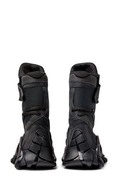 the back view of a pair of black boots on a white background with no shoes