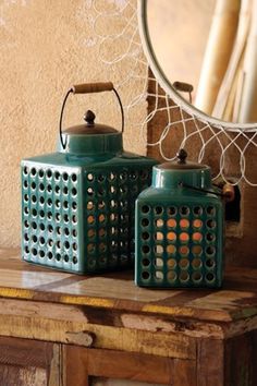 two tea kettles sitting on top of a wooden table in front of a mirror